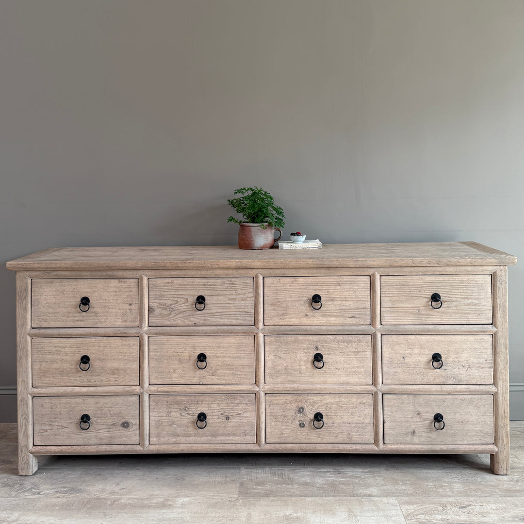 Wooden dresser with multiple drawers against a plain wall