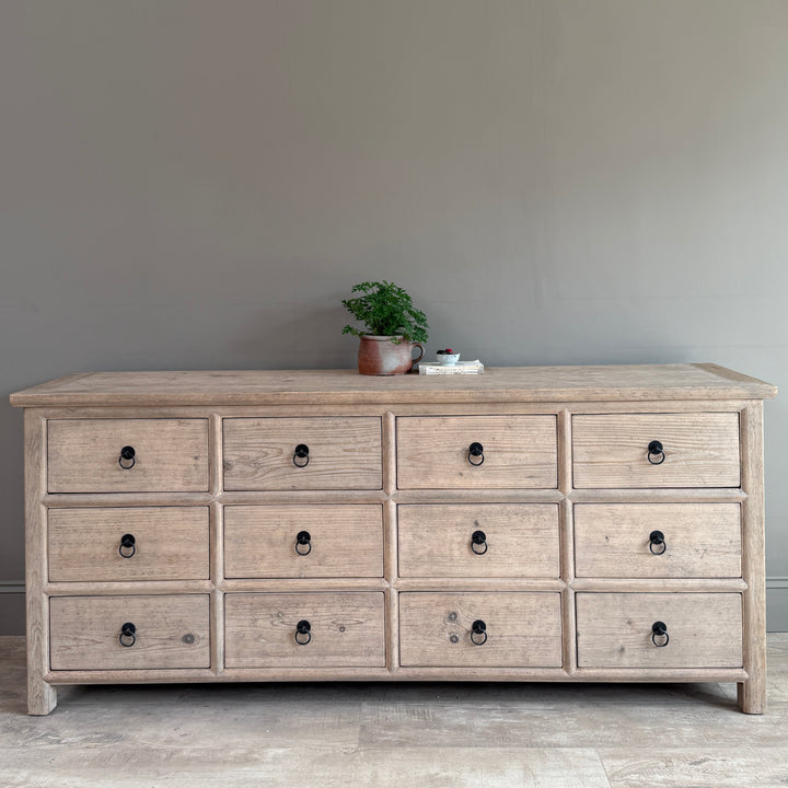 Wooden dresser with multiple drawers against a plain wall