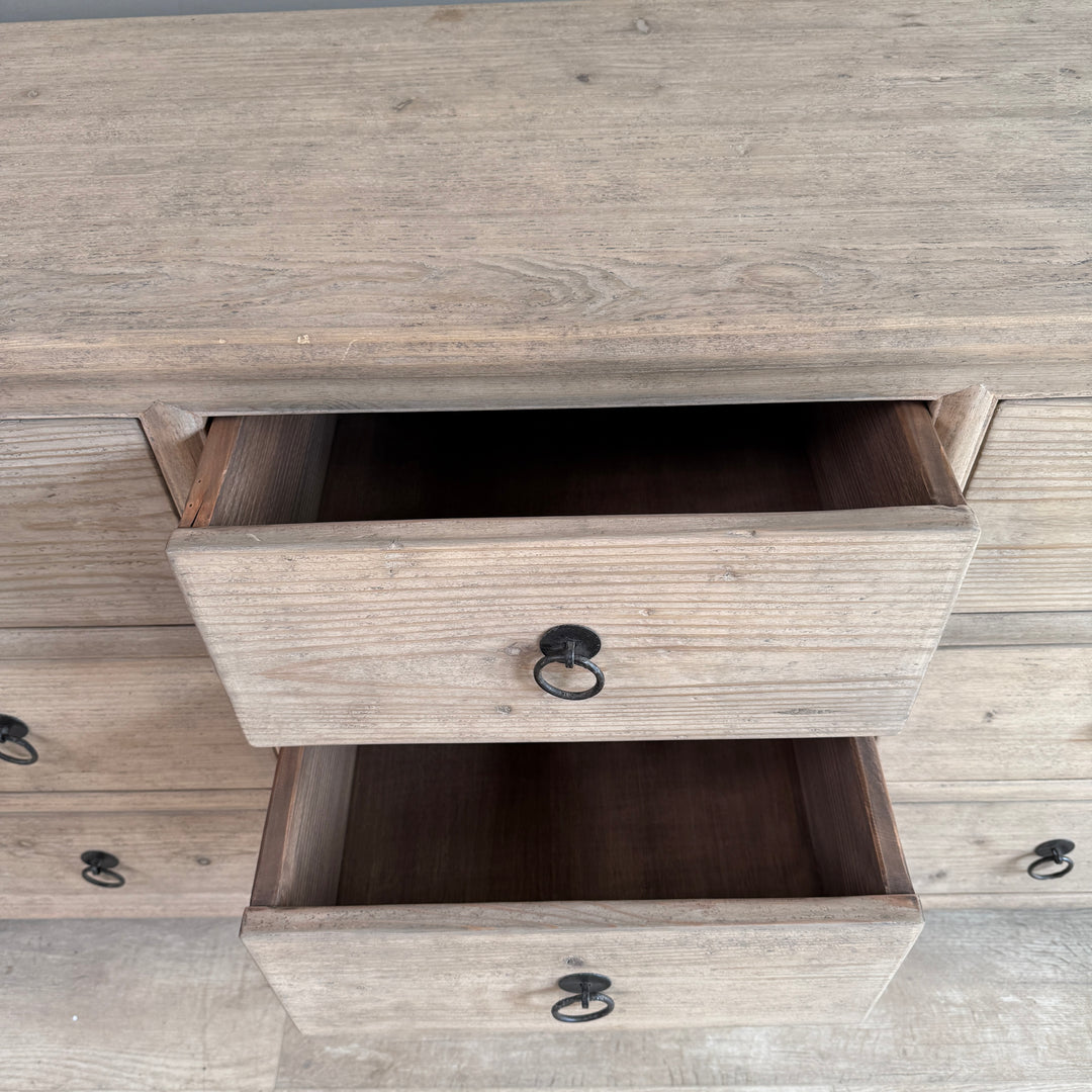 Wooden dresser with open drawer showing a neutral color scheme.