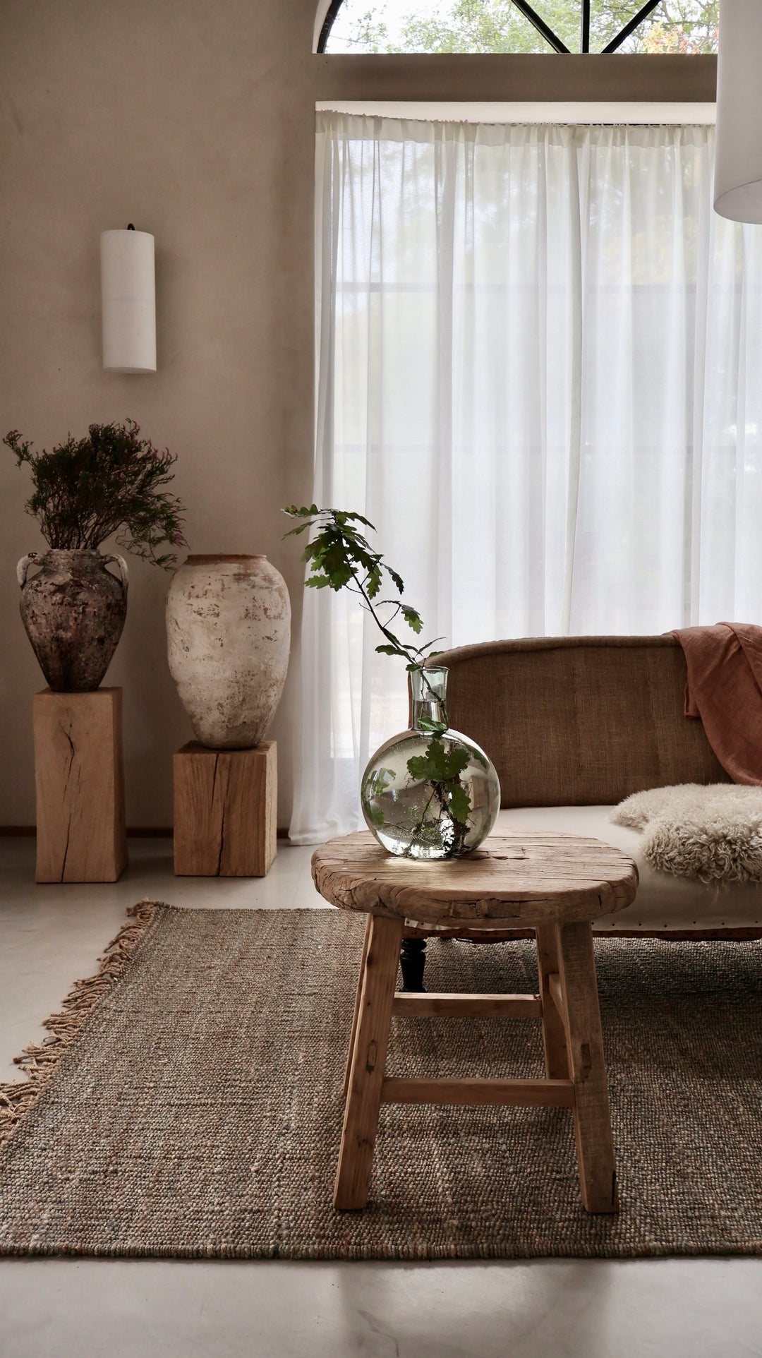 Large reclaimed elm round side table in a room with an arched window