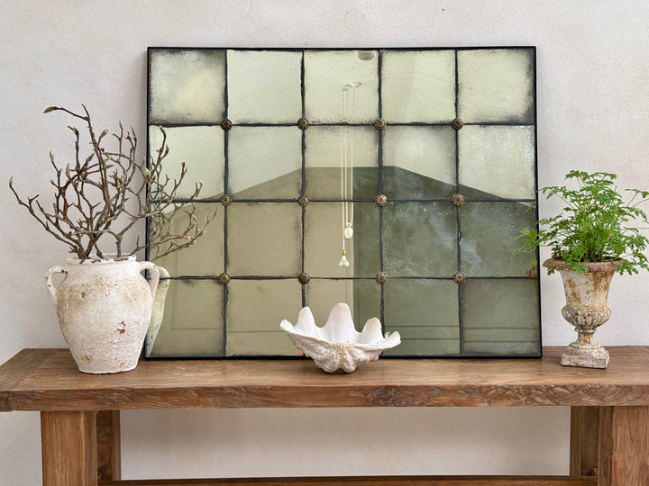 Large Leonora foxed antiqued mirror displayed on a reclaimed wood console table, creating a timeless focal point for an entrance hall, living room or dining room.