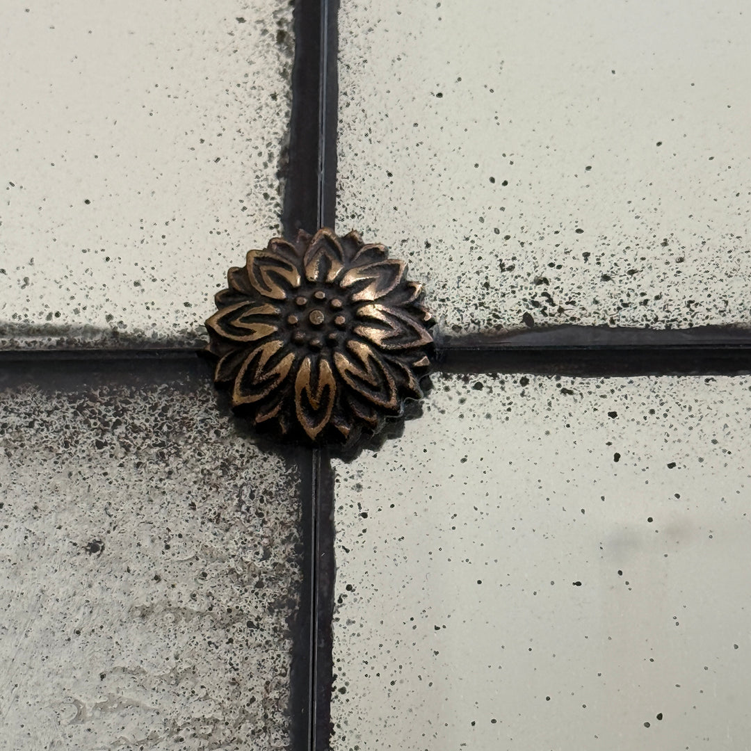 Close-up detail of the Leonora foxed antiqued mirror showing the handcrafted brass rosette and individually distressed Verre Églomisé mirror panes.