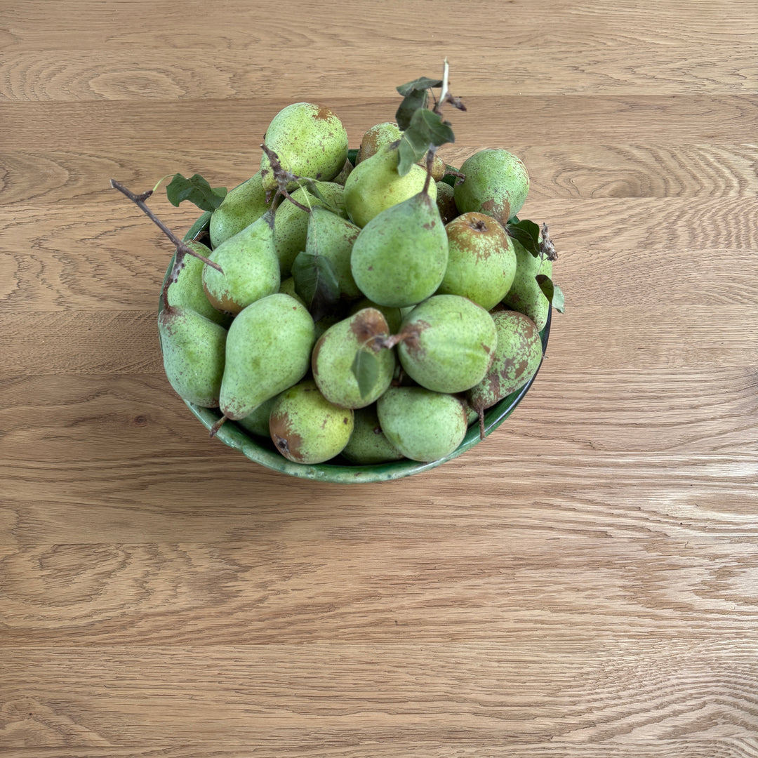 Overhead view of the reclaimed American oak tabletop with a bowl of green pears, showing its natural grain and understated matt finish.