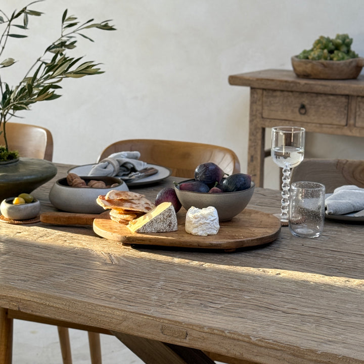 Close-up of the Reclaimed Elm Farmhouse Dining Table Cambridge, showcasing the rich character of reclaimed elm timber styled for relaxed entertaining. Natural textures, artisan tableware and warm evening light highlight the table&