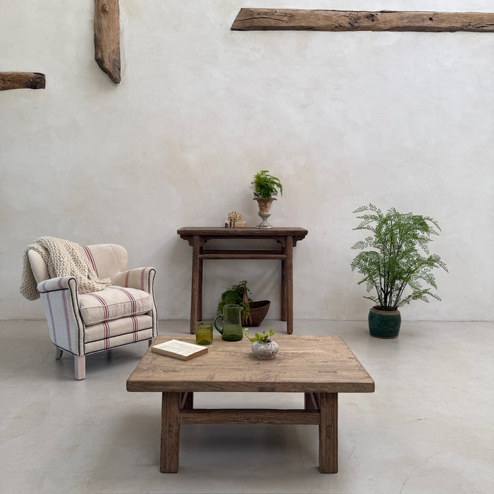 Living room with wooden furniture, plants, and a plaid armchair.