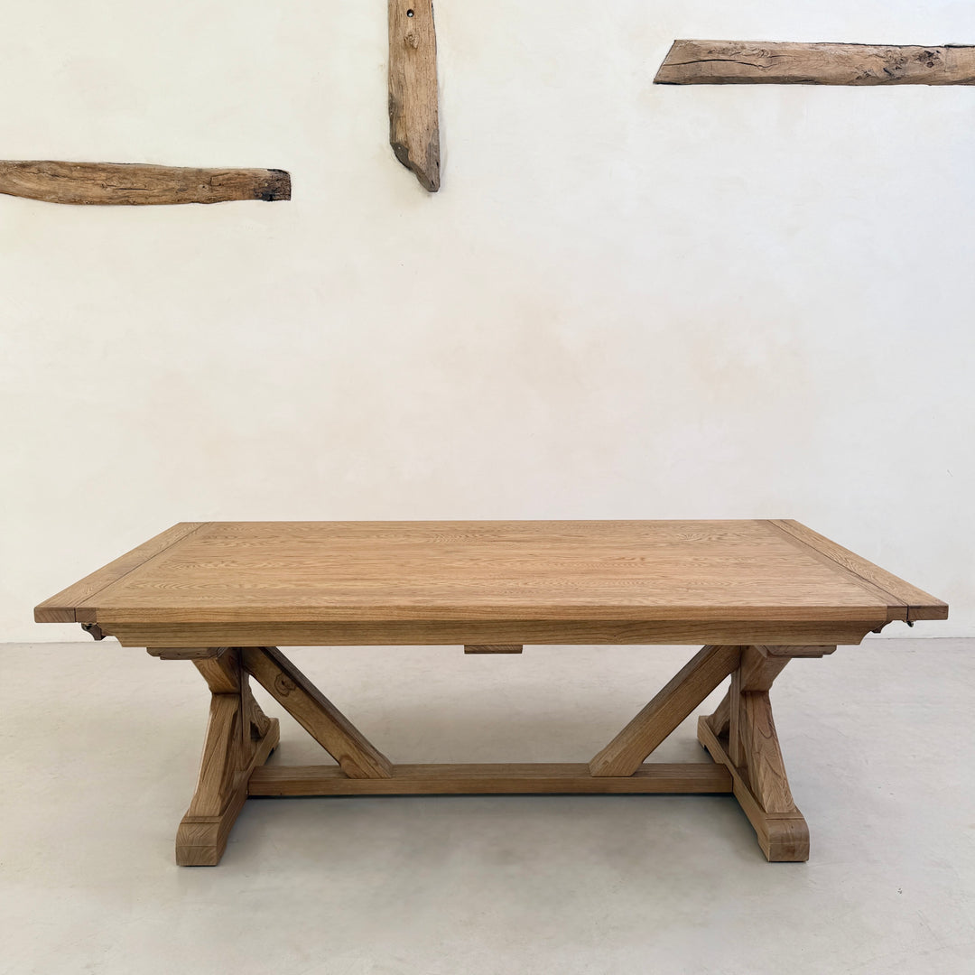 Reclaimed solid oak dining table shown without chairs, highlighting the substantial tabletop and architectural cross-frame trestle base.