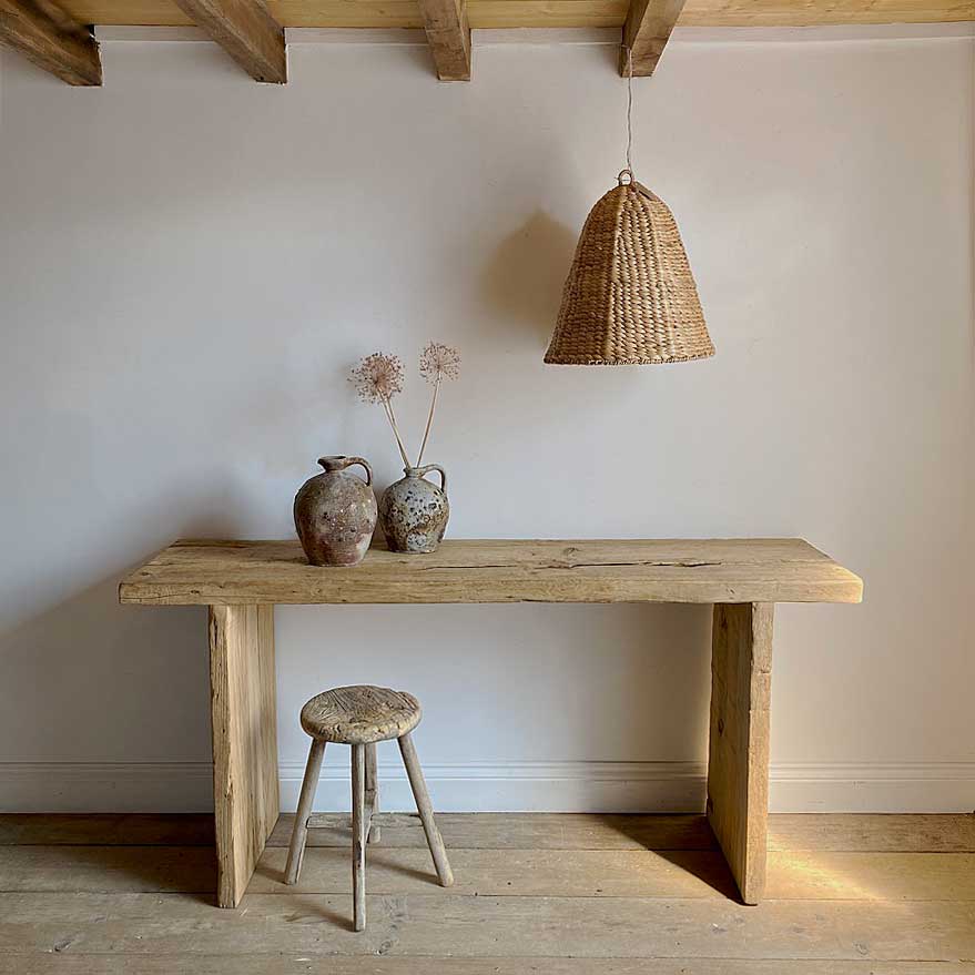 Rustic Reclaimed Wood St Ives Console Table simply styled with a rustic antique stool below rattan lighting