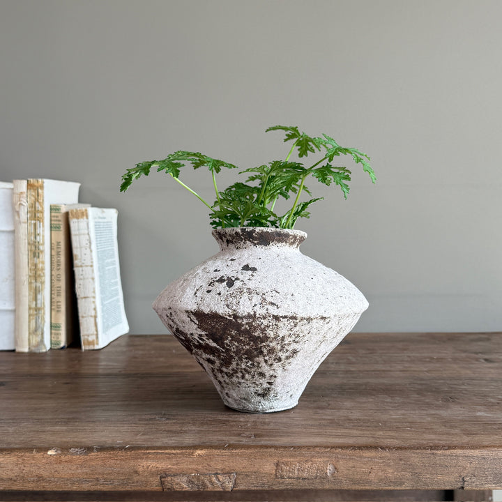 Rustic stoneware decorative vase with an aged textured finish, styled with faux greenery on a reclaimed wooden console in a contemporary country interior.
