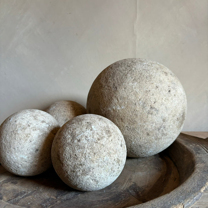 Rustic aged sandstone spheres styled together in a rustic wooden bowl