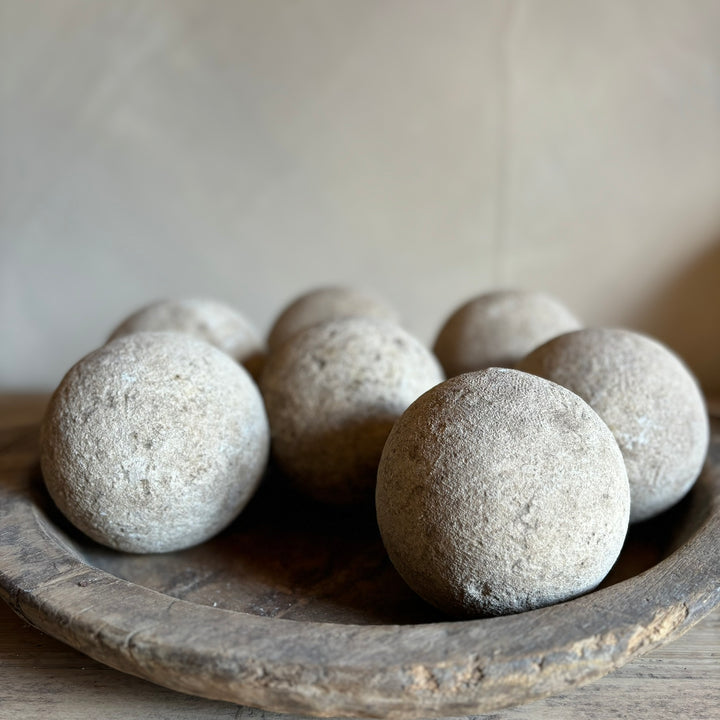 Rustic aged sandstone sphere smaller size in a rustic wooden chapati bowl