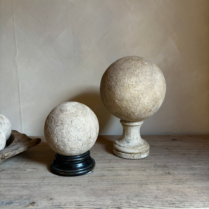 Rustic aged sandstone sphere on wooden and sandstone stands