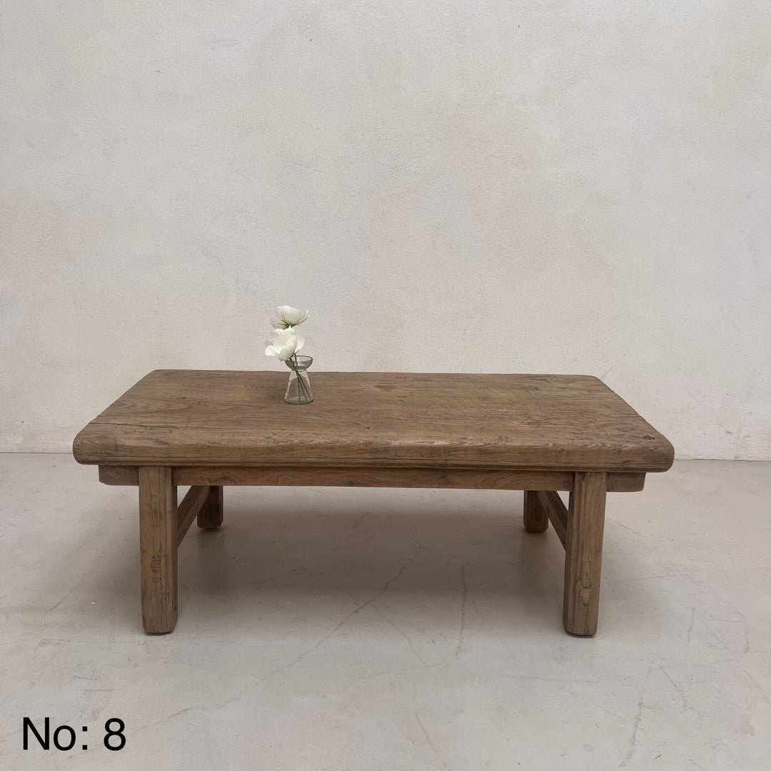 Wooden table with a vase of flowers on a plain background