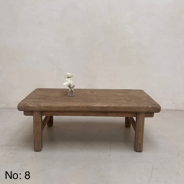 Wooden table with a vase of flowers on a plain background