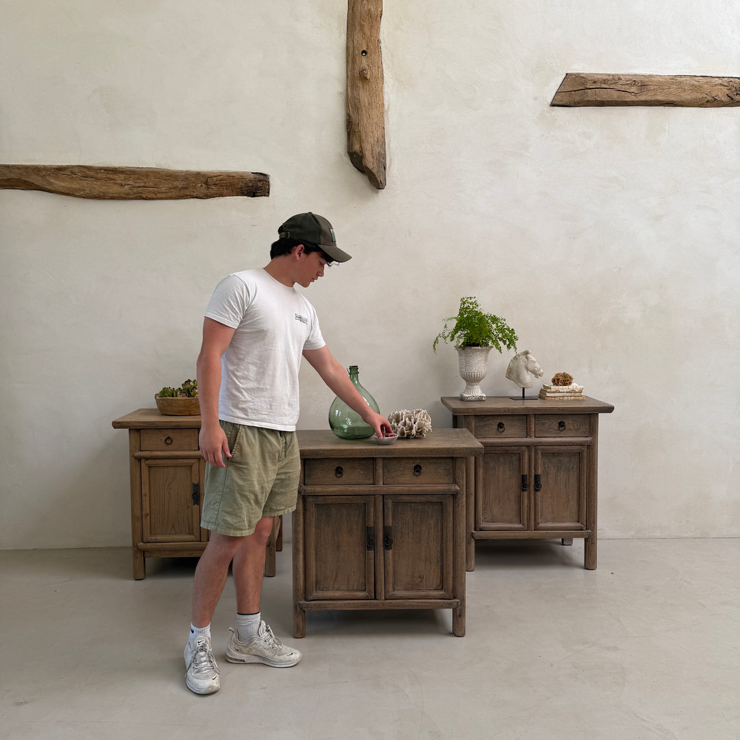 Person interacting with wooden furniture in a minimalistic room.