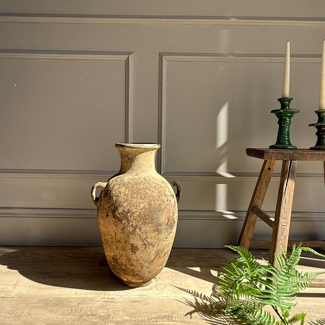Vintage-style vase on a wooden floor with a neutral wall background