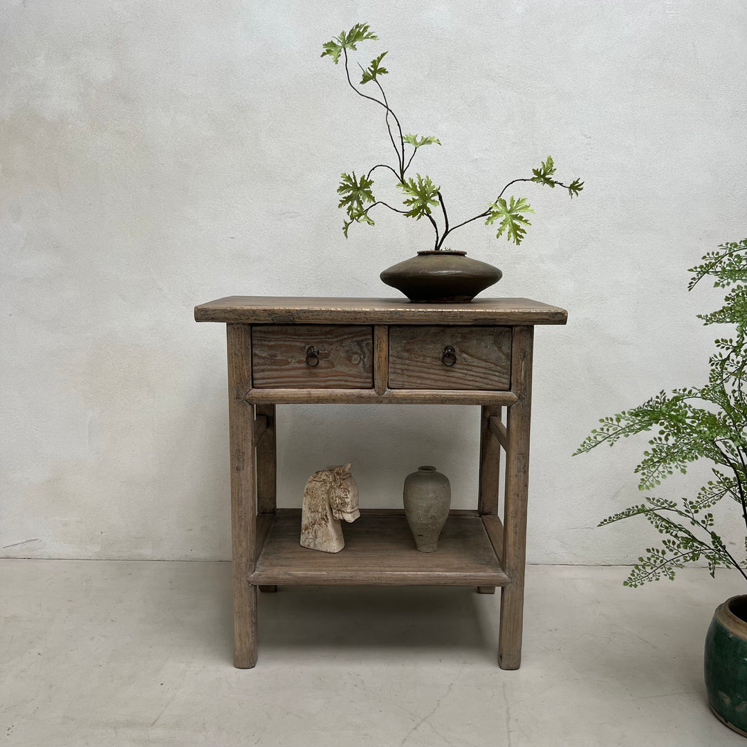 Wooden side table with a vase and branches on a plain background
