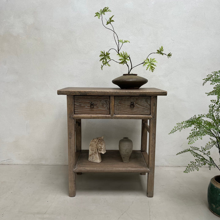 Wooden side table with a vase and branches on a plain background