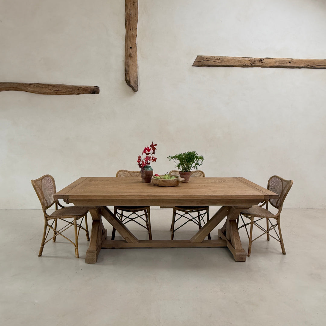 Reclaimed American oak extending dining table styled with classic wooden chairs and simple floral arrangements.