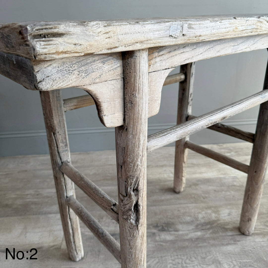 Vintage wooden stool with a weathered finish on a wooden floor.