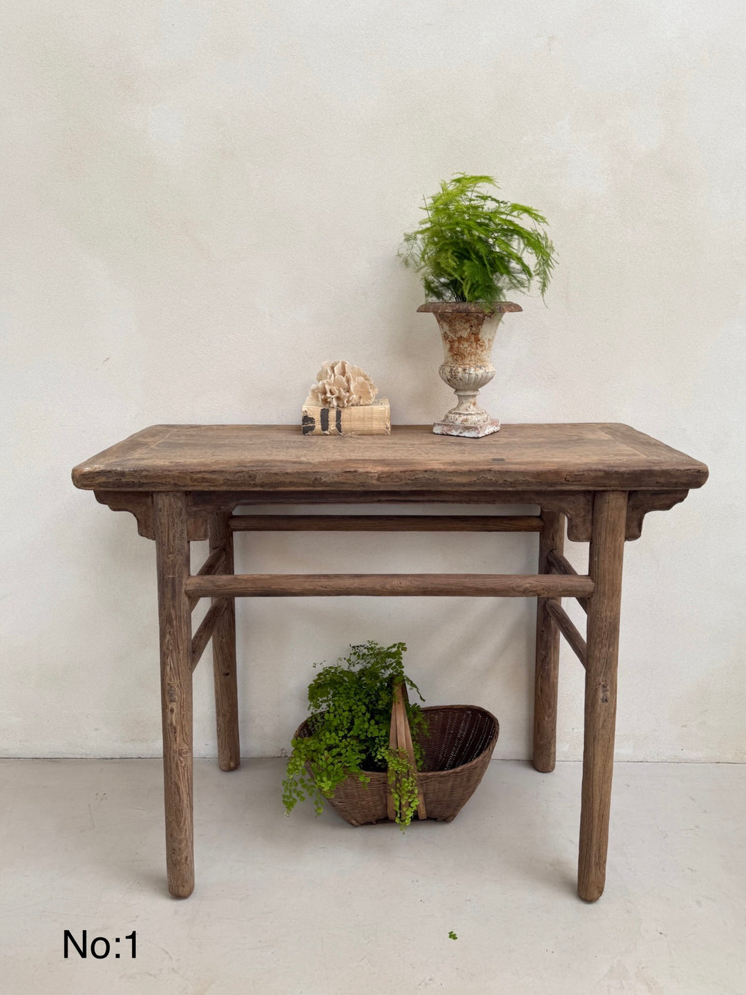 Wooden console table with decorative items against a white wall