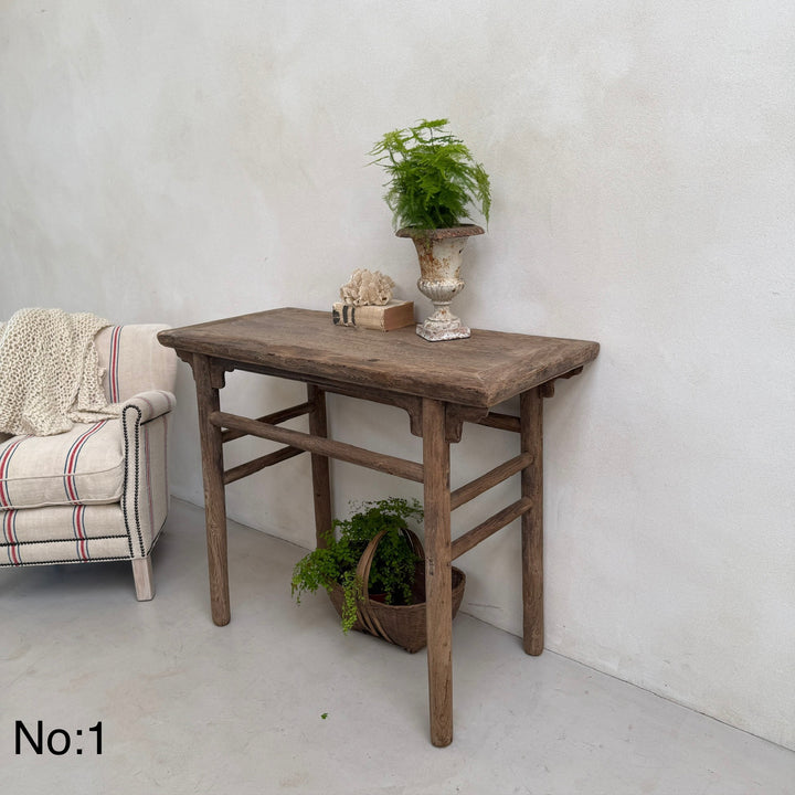 Wooden table with decorative items against a white wall