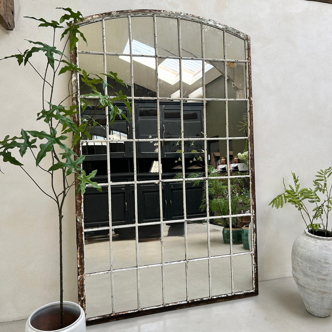 Large decorative mirror with a grid pattern in a room with plants