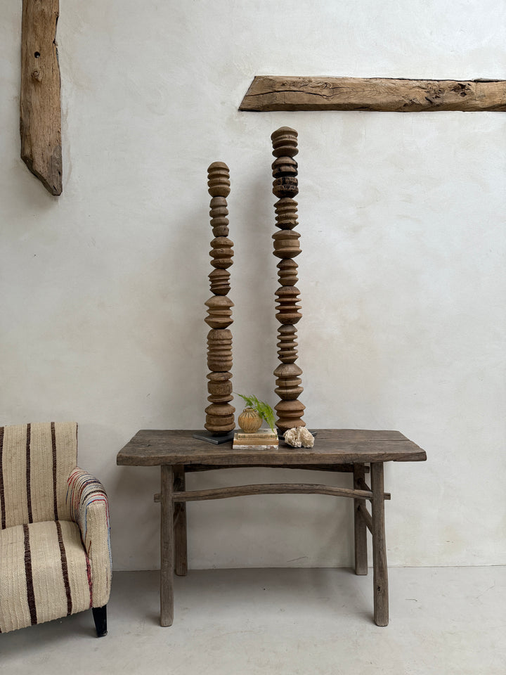 Wooden chair against a textured wall with a plant on it