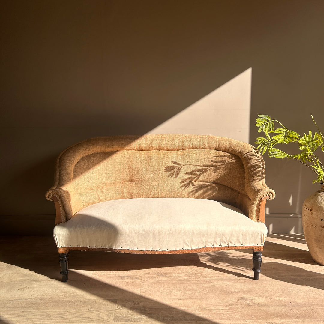 Antique French deconstructed sofa Louis with curved back, exposed natural hessian upholstery, cream seat and original dark timber legs.