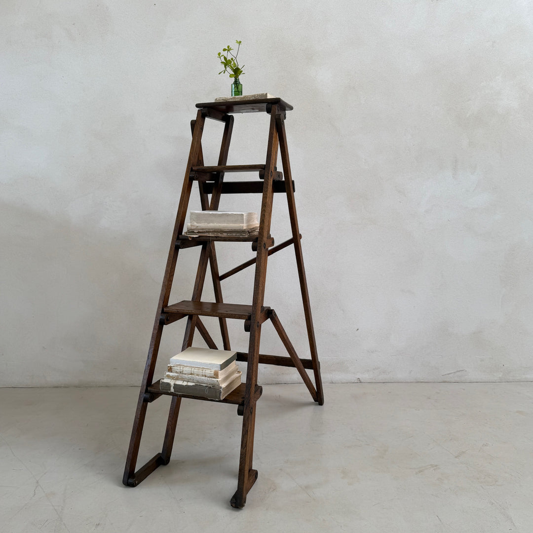 Angled view of the Antique English Library Ladder Margot with its collapsible frame and four solid steps.
