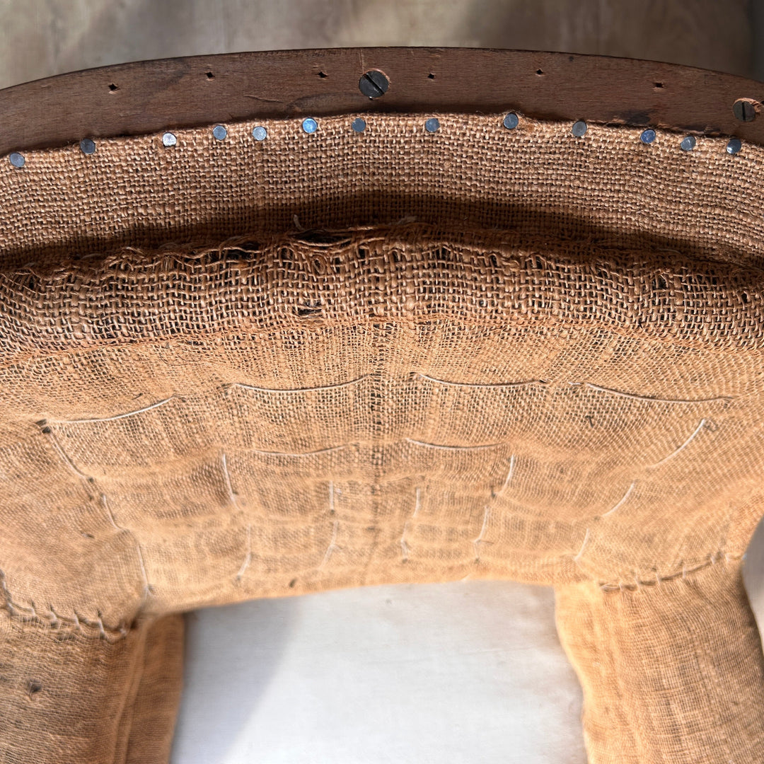 Close-up of original woven hessian upholstery on a French antique armchair, highlighting the aged fabric, traditional stitching and exposed upholstery tacks.