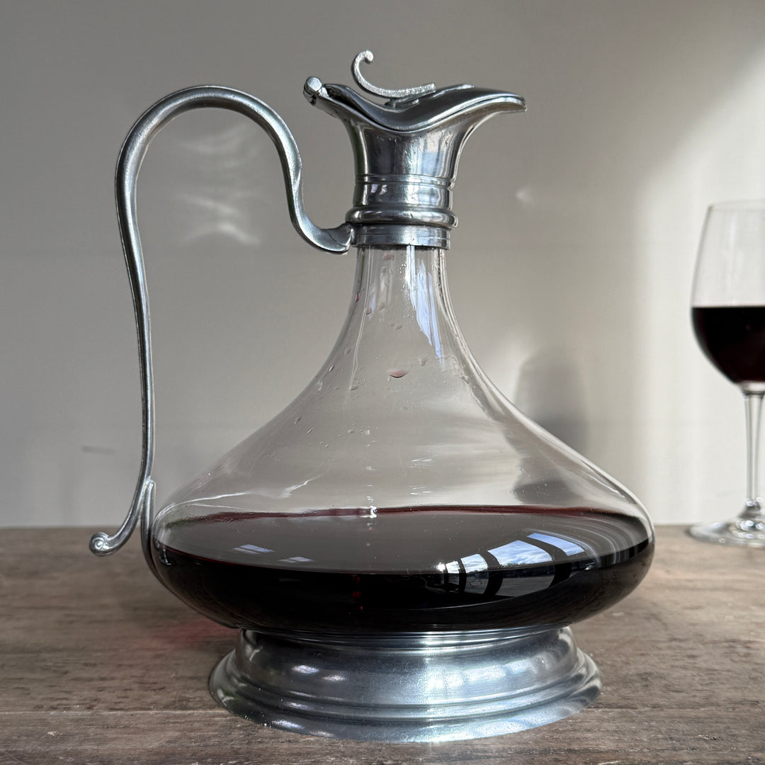 Side view of a French glass red wine decanter featuring a wide rounded body, pewter pedestal base and elegant curved pouring handle.