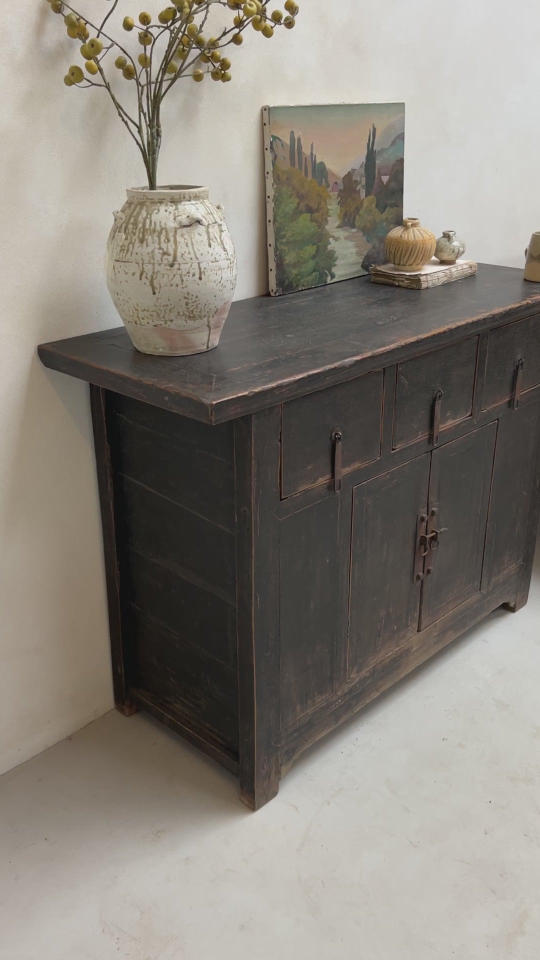 Black antique cupboard styled with vintage oil painting and antique vases.