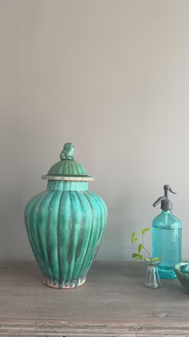 Video showing a green glazed stoneware temple jar from multiple angles, highlighting its sculptural shape, bird finial and crackle glaze finish.
