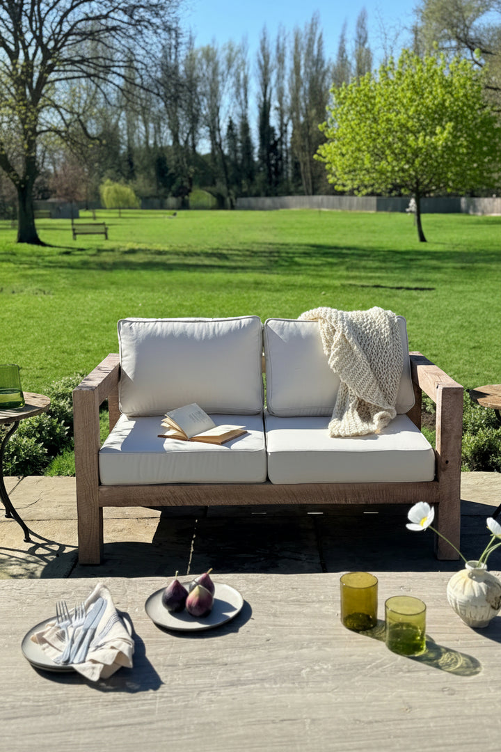 Outdoor setting with a wooden sofa, table, and garden view