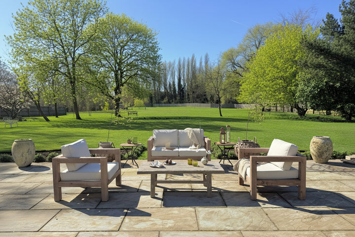 Outdoor patio set with furniture on a stone patio, surrounded by greenery.