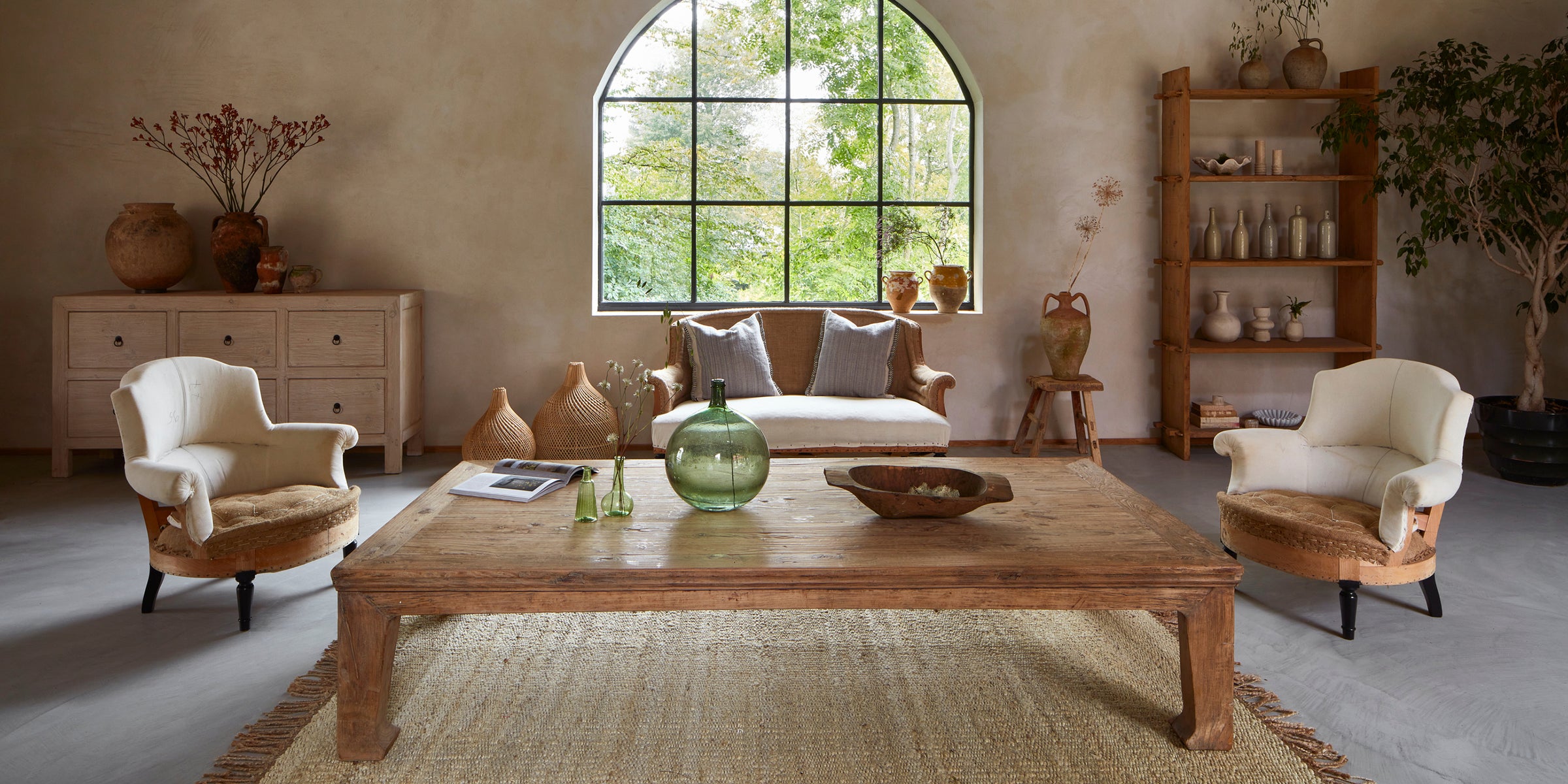 Well lit living room with wooden coffee table, beautiful armchairs and decor.